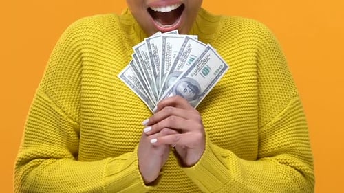 Aufgeregte afroamerikanische Frau zeigt Dollars auf hellem Hintergrund, Investition