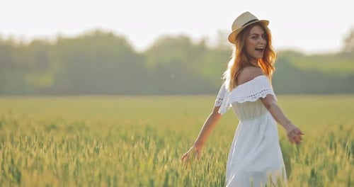 Happy Girl in a Hat Whirls in the Field in Summer