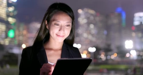 Young Adult Woman Using Tablet in the City at Night