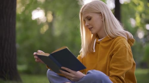 Junge hübsche Frau liest einen Abenteuerroman mit Interesse an der Natur