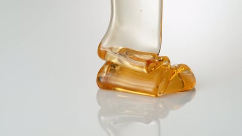 Pouring honey on reflective surface. Slow Motion.