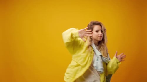 Woman Professional Dancer Dancing in Studio Against Yellow Background