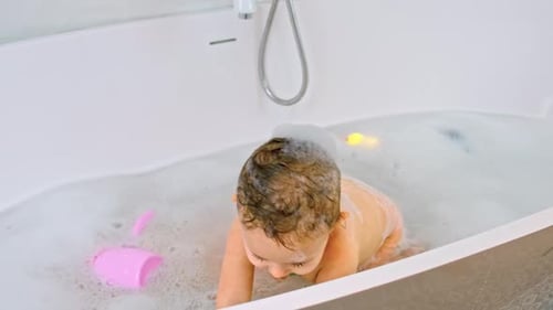 Baby Plays in the Bath With Bubbles