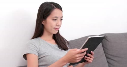 Woman Using Tablet Device, Relaxing Indoors on Sofa