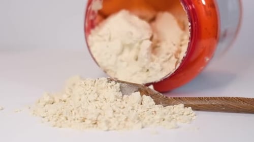 Protein Powder Spills From Jar With Wooden Spoon