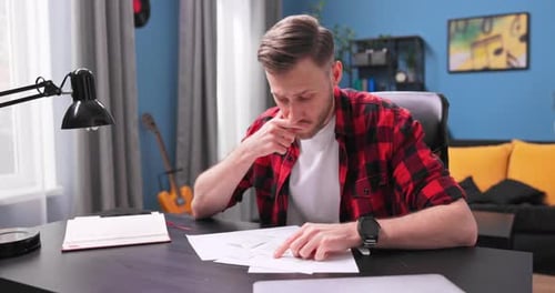 Man Analyzing Documents at Desk in Home Office
