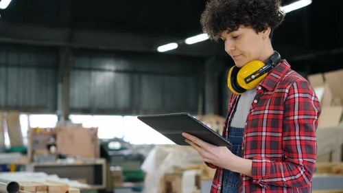 Young Woman Using Tablet in Wood Workshop Looking Around and Touching Screen