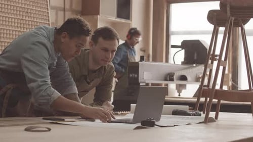 Carpenters Operating CNC Machine with Laptop
