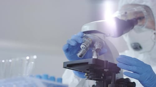 Medical Scientist Looking at Sample under Microscope