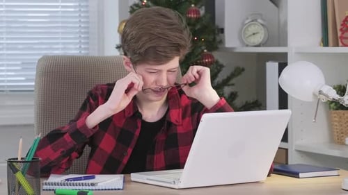 Tired Teen Student Using Laptop at Desk