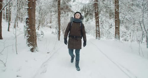 Wide Angle Steady Shot Man Hiker Walks Along Trail in Snow Covered Winter Forest