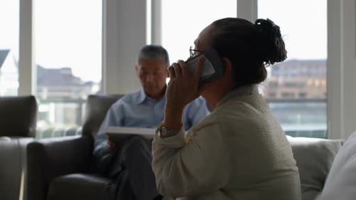 Side view of old senior asian woman talking on mobile phone in a comfortable home 4k