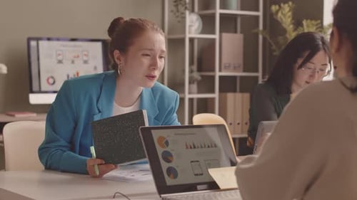 Businesswomen Discussing Marketing Statistics in Office