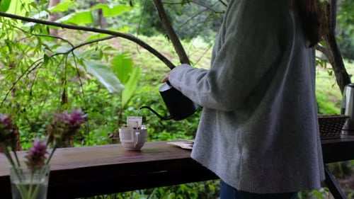 Woman Pouring Over Coffee Outside in Lush Setting
