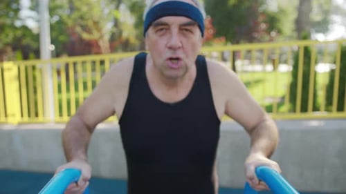 A Retired Elderly Man Works Out on a Sports Ground Outside. Healthy Lifestyle Concept.