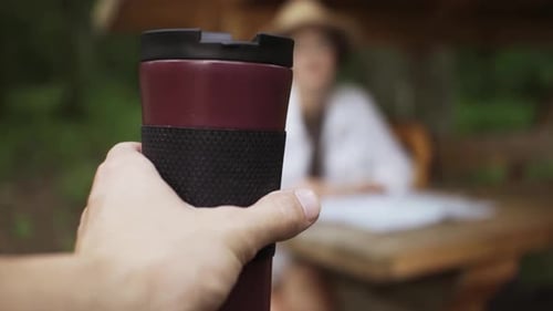 Hand Holds Travel Mug in Forest