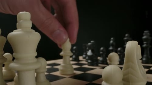 Man's Hand Moving White Bishop Chess Piece From First Line
