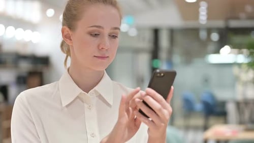 Young Woman Uses Smartphone in Modern Workplace