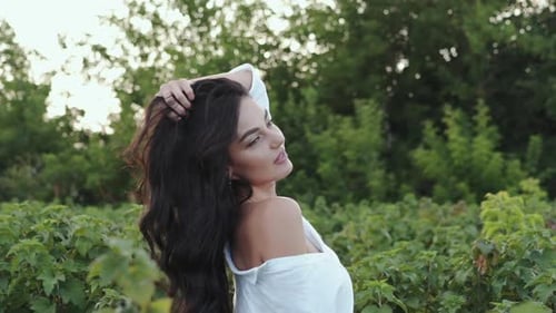 Attractive Woman Posing with Long Hair and Gazing Into Camera Among Plantation