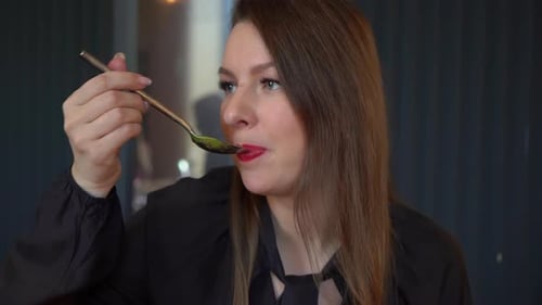 Woman Enjoying Green Soup with a Spoon