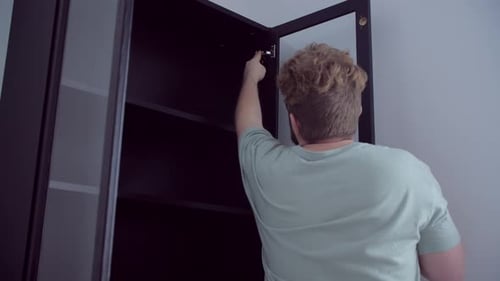 Man Adjusting Hinge on Black Cabinet in Home