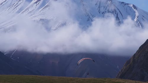 Gleitschirmfliegen in den verschneiten Bergen