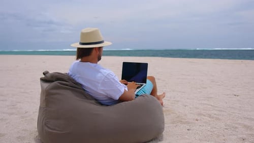 Man Working on Laptop on Beach
