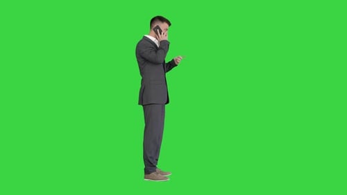 Business Man in a Suit Talking with Mobile Phone on a Green Screen Chroma Key