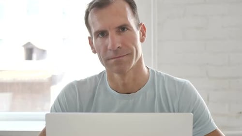 Smiling Man Giving Thumbs Up in Front of Laptop