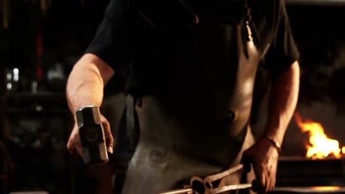 Blacksmith Shapes Hot Metal with Hammer in Workshop