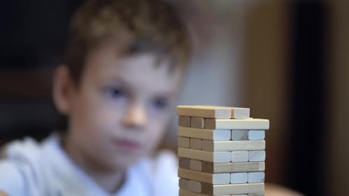 Junge spielt zu Hause im Brettspiel mit Holzturm
