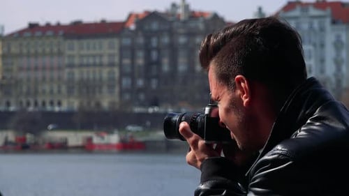 A Young Man Takes Photos of a Quaint Town with a Camera - Closeup
