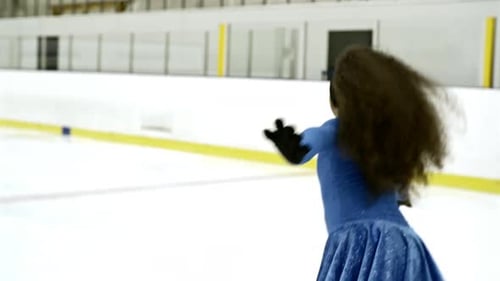 Girl in Blue Dress Spins on Ice Skates