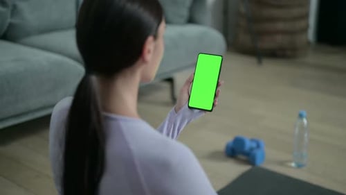 Rear View of Latin Woman Using Smartphone with Chroma Screen on Yoga Mat