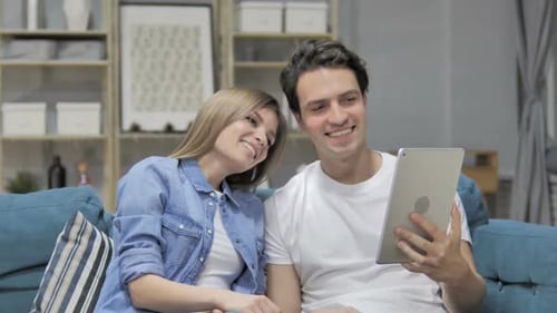 Smiling Young Couple Video Chatting on Tablet at Home