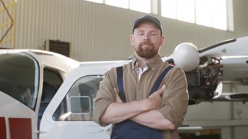 Aircraft Mechanic in Airplane Hangar with Arms Crossed