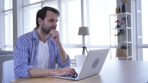 Man Typing on Laptop at Home Desk