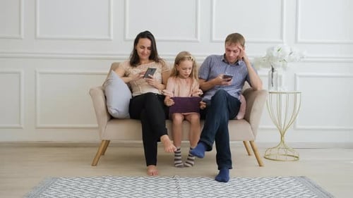 Family Using Technology Together on Couch Indoors