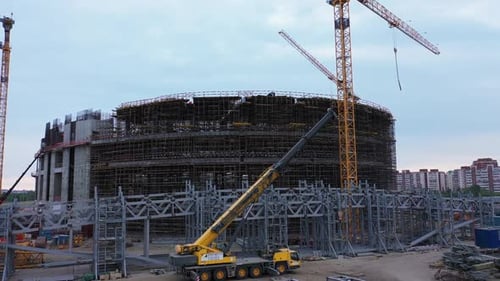 Edificio de arena deportiva con carcasa metálica y grúas torre