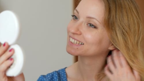 Lächelnde Blondine mit langem, welligem Haar, Kopf drehen und in die Kamera