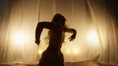 Silhouette of a Professional Dancer Performing in Studio in Soft Warm Lighting