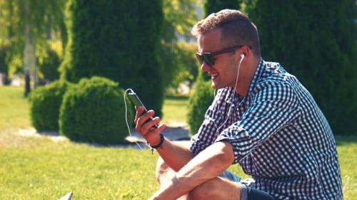 Man Enjoying Smartphone in Sunny Urban Park