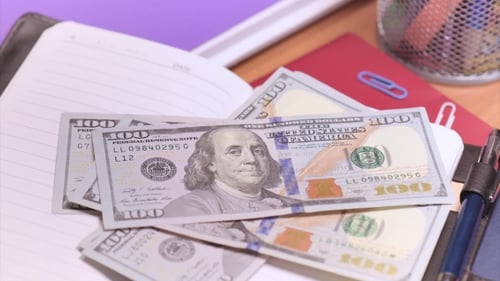 Pile of Hundred Dollar Bills on Open Notebook