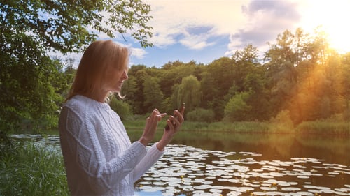 Beautiful Girl Using SmartPhone Sitting Near Lake in City Park 1