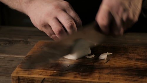 Close - Up Of The Chief's Hands Cutting Onion On a Wooden Board