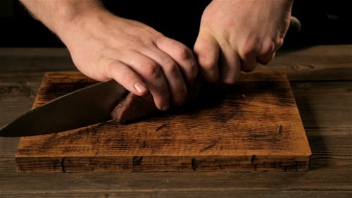 Chef Slices Cooked Meat on Cutting Board
