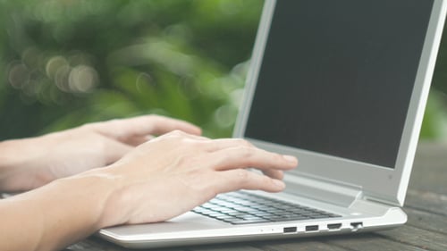 Hands Typing on Laptop Keyboard in Nature