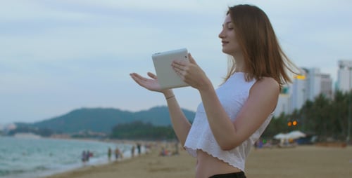 Mädchen spricht mit Tablet am Meer