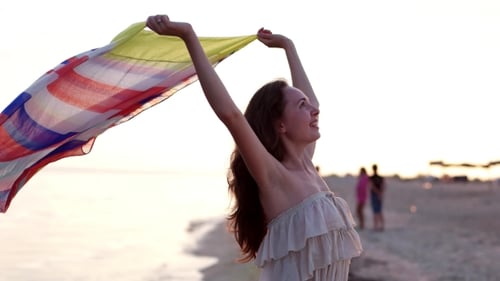 Woman with Scarf Enjoying Sunset at the Beach