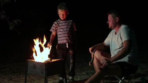 La famille se repose dans le camp la nuit près d'un feu de camp